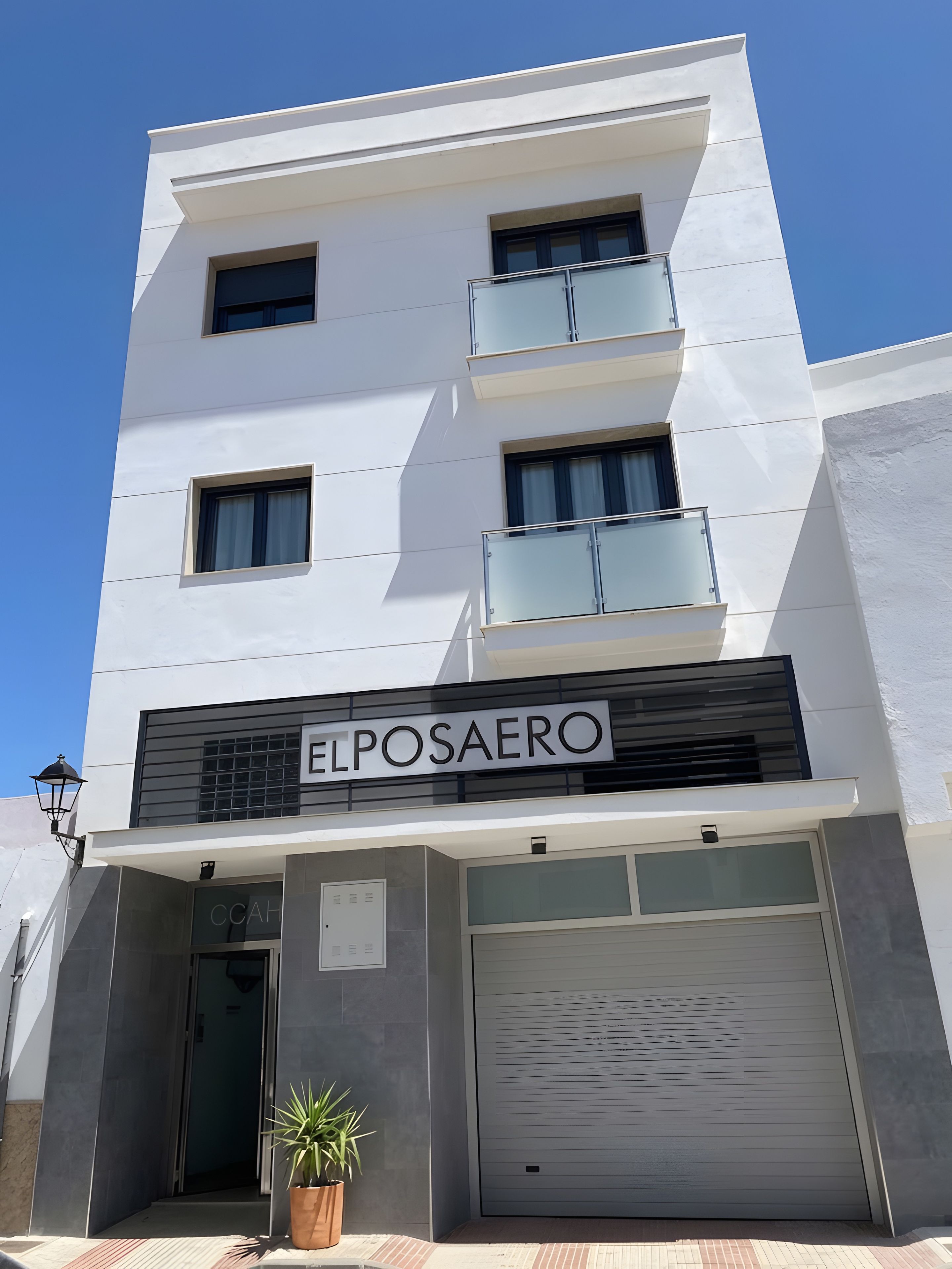 A modern building with a sign reading 'ELPOSAERO' and a closed garage door.