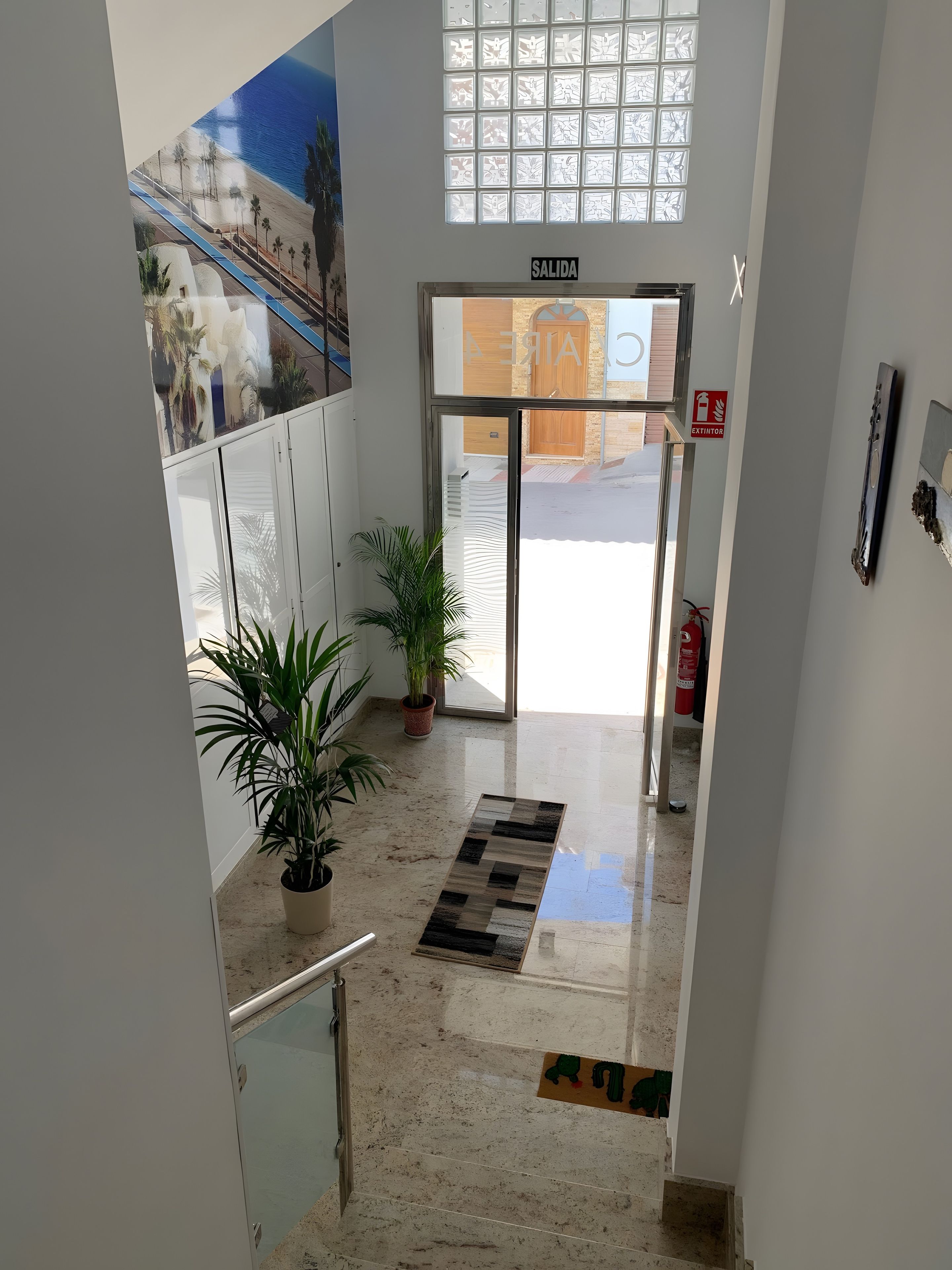 A hotel entrance with a glass door, a sign reading 'SALIDA,' and a fire extinguisher mounted on the wall.