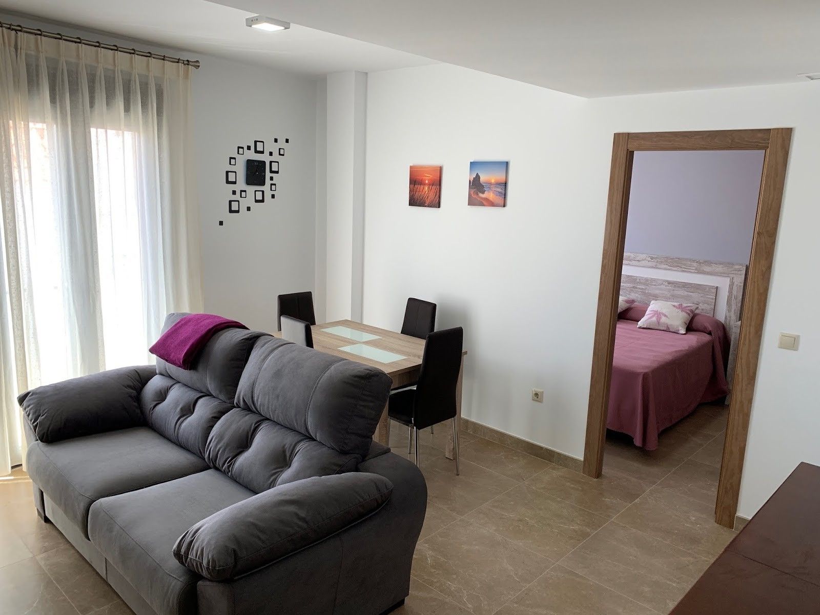 A modern living space with a sofa, a dining table with chairs, and a bed with a headboard.