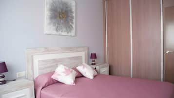Een slaapkamer met een bed, nachtkastje, lamp en een kledingkast.