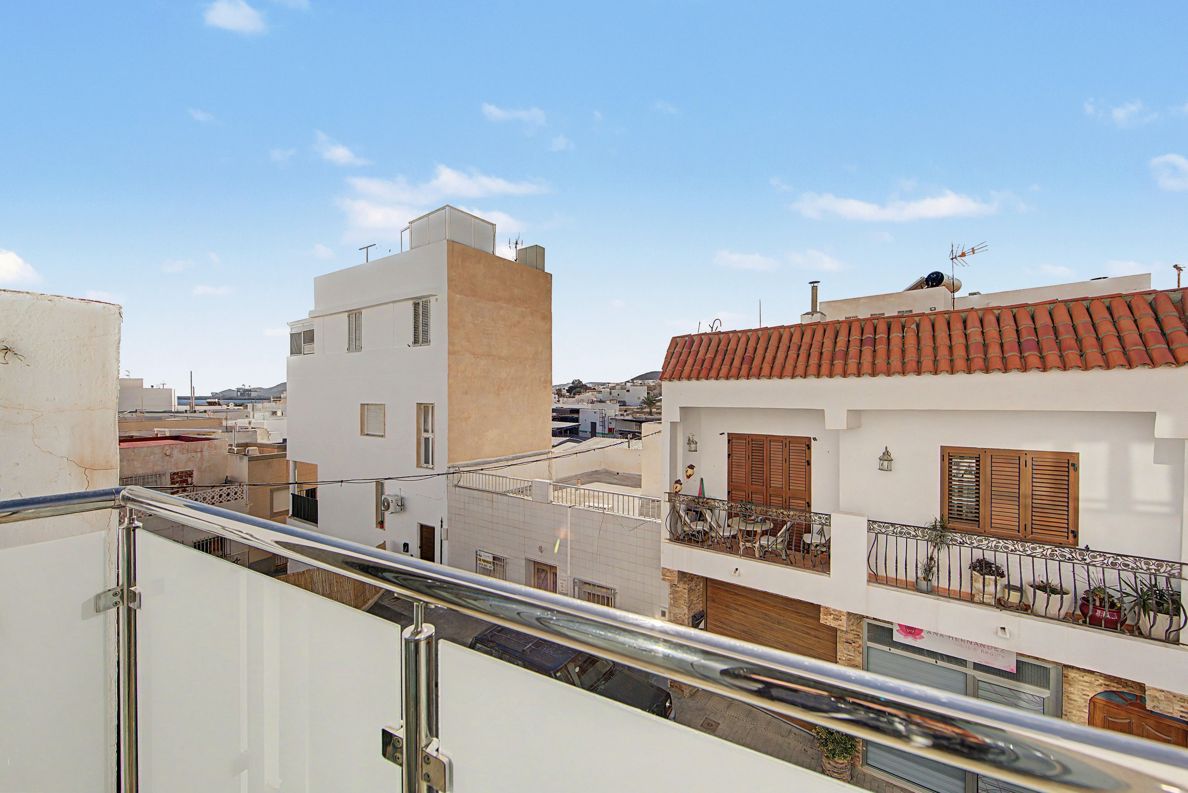 A residential building with a balcony, a tiled roof, and a clear sky.