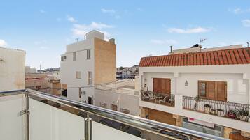 A residential building with a balcony, a tiled roof, and a clear sky.