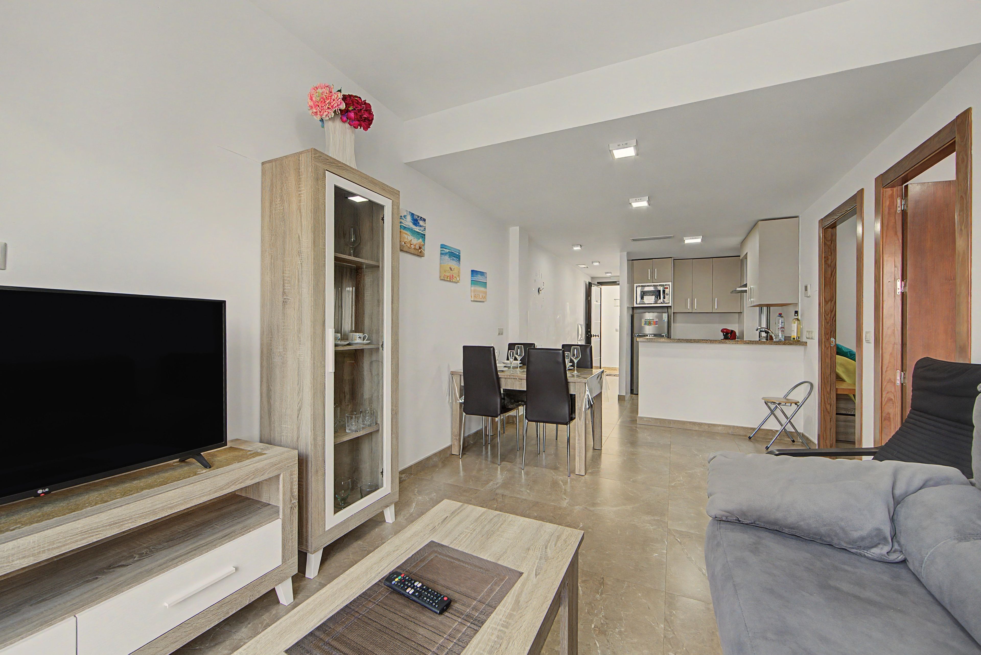 Una sala moderna con un televisor de pantalla plana, un sofá y un comedor con sillas y una mesa.