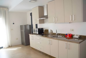 Eine moderne Küche mit Edelstahlgeräten, beigen Schränken und einer Arbeitsplatte aus Granit.