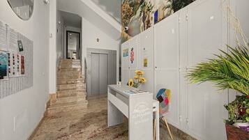 A hallway with a staircase, a reception desk, and a wall with various notices.