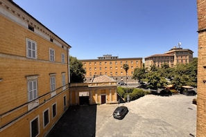 A courtyard with a parked car, buildings with uniform architecture, and a clear sky. - T. R. B. Home - Piazza Gramsci (Siena)