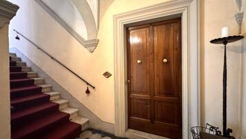 Una scala con gradini rivestiti di tappeto rosso che conduce a una porta in legno con maniglie in ottone.