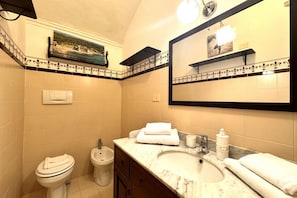 A bathroom with a toilet, bidet, sink, and mirror. - T. R. B. Home - Piazza Gramsci (Siena)