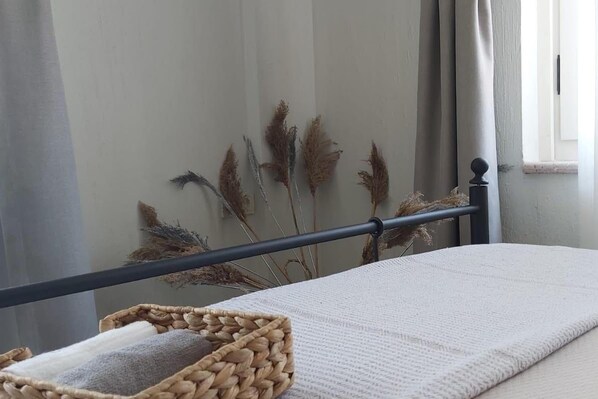 A bed with a white sheet, a woven basket, and dried pampas grass against a wall. - Luna Ria Konuk Evi (Ayvalik)