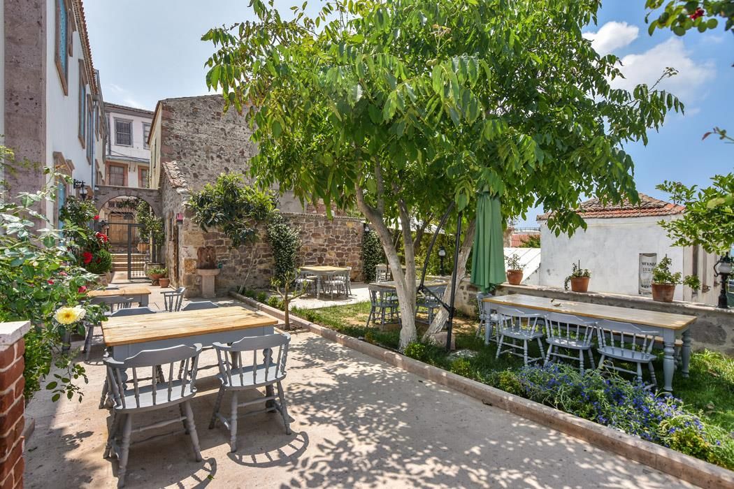 Un espace extérieur aménagé avec des tables et des chaises, entouré de verdure et de murs en pierre.