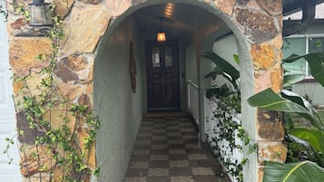 A stone archway leading to a hallway with patterned flooring and a door at the end.
