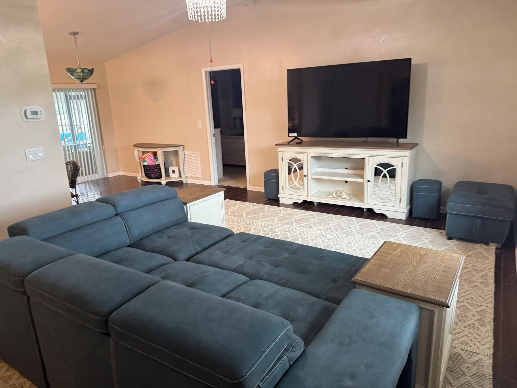 A living room with a sectional sofa, a television on a stand, and a patterned rug.