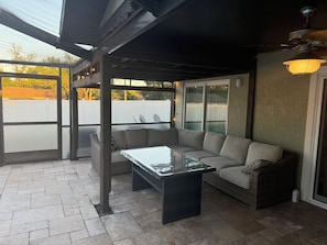 A covered patio area with a sectional sofa, a glass-top coffee table, and a wicker chair. - Minutes to Mermaids (Spring Hill)