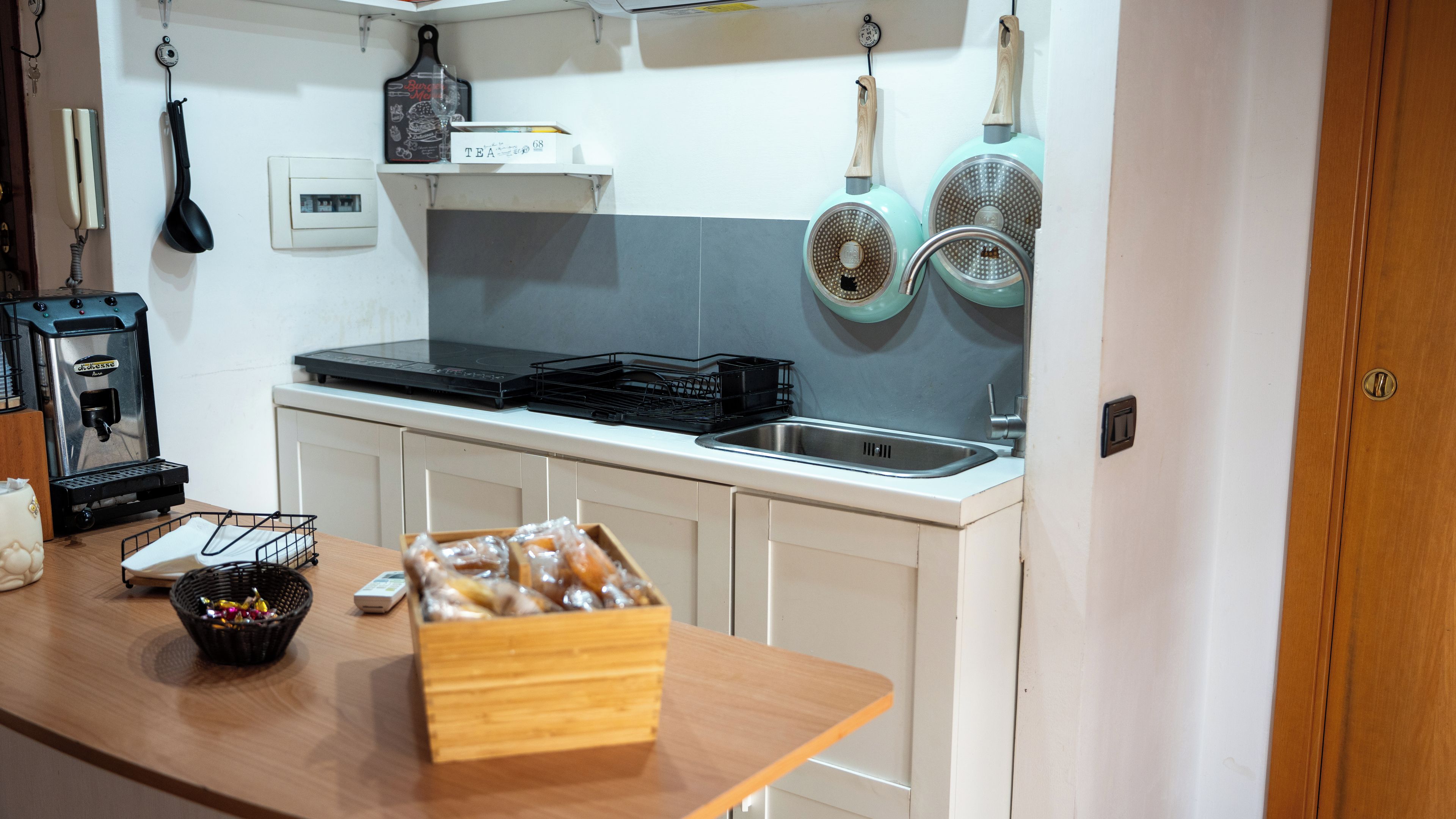 Una cocina con cafetera, hervidor y una caja de té.