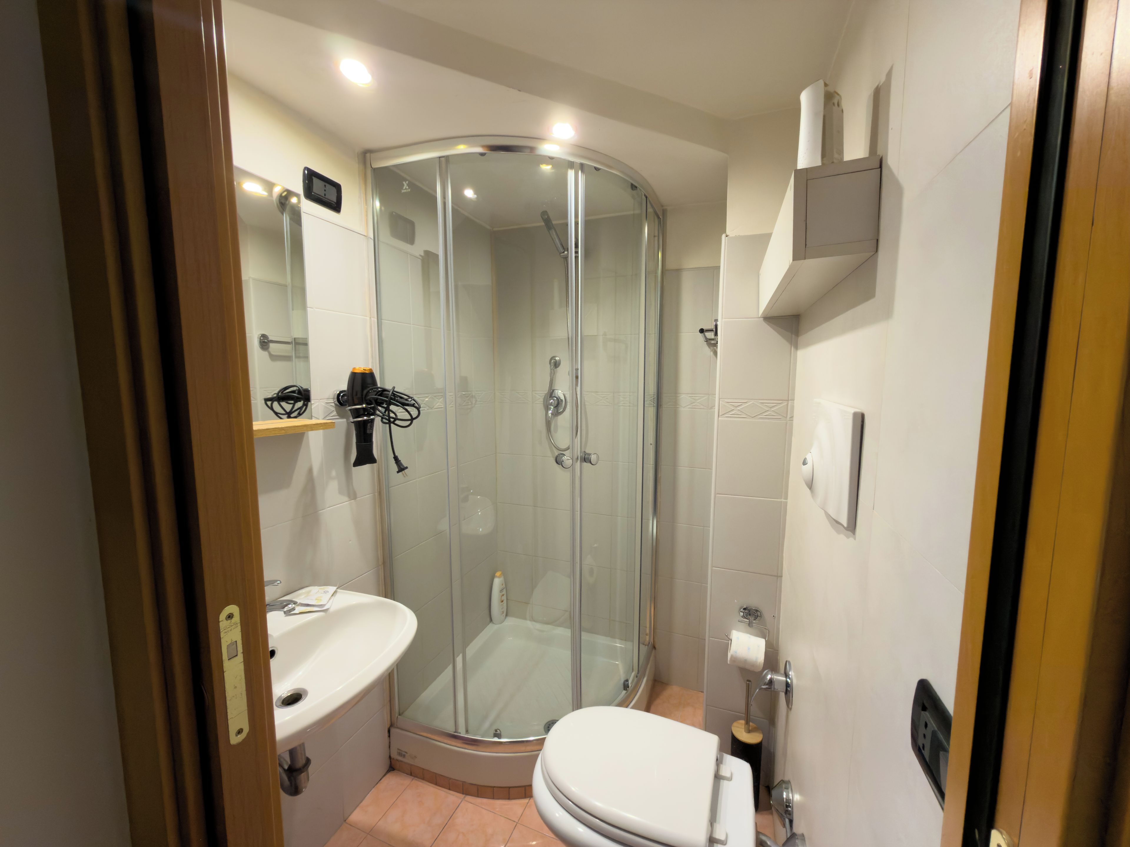 Un baño moderno con ducha envuelta en vidrio, lavamanos blanco y retrete.