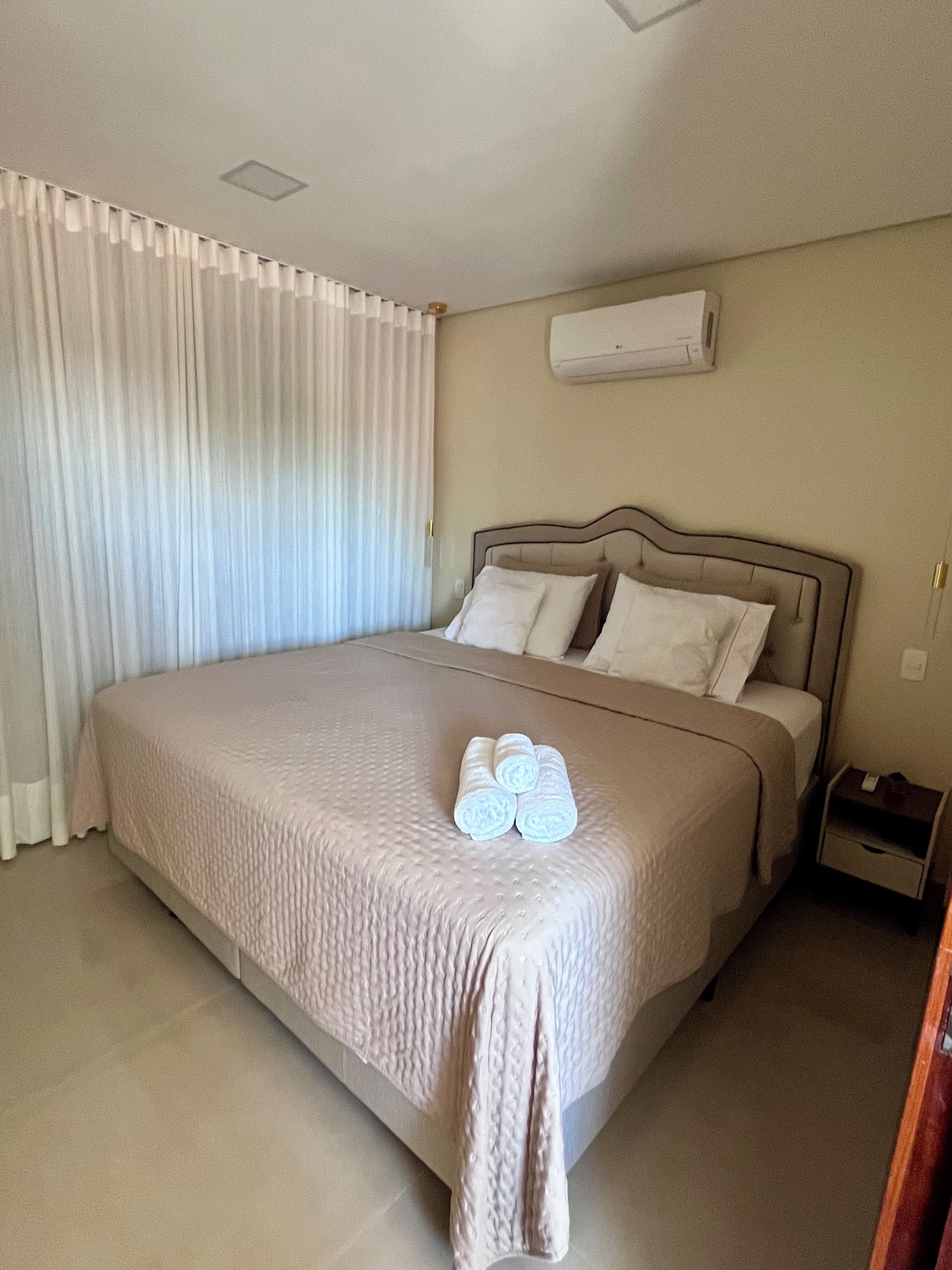 Habitación de hotel con una cama grande, una mesita de noche y un equipo de aire acondicionado en la pared.