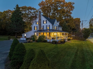 Une maison à deux étages avec un porche, une cheminée en pierre et une pelouse bien entretenue.