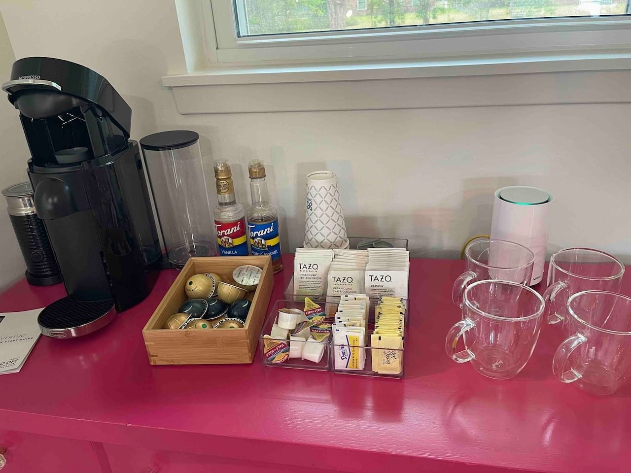 Eine Kaffeestation mit einer Kaffeemaschine, Kaffeetassen, einer Kapselbox, einem Behälter mit Torani-Sirup und einem Tazo-Tee-Spender.