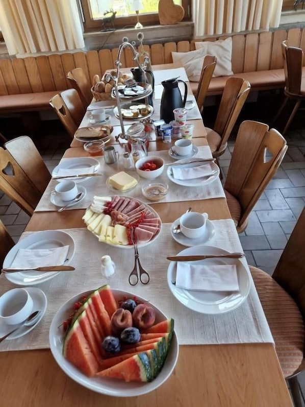 A breakfast setup with a variety of food items, including fruits, pastries, and a tea service.