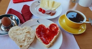 A table with plates of food, a cup of coffee, and a red napkin.