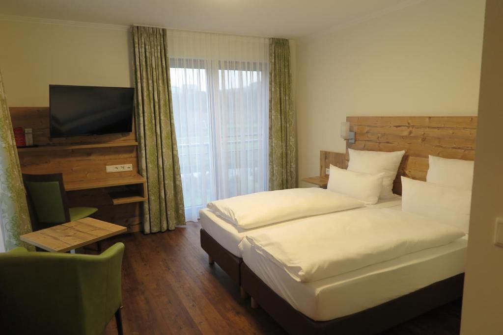 A hotel room with a bed, a TV, a desk, and a chair.