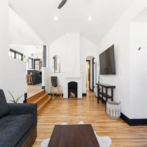 Ein großzügiges Wohnzimmer mit Kamin, einer Couch, einem Couchtisch und einem an der Wand befestigten Fernseher.