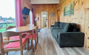 Une pièce aux murs lambrissés, avec une table et des chaises, un canapé et un tableau accroché au mur.