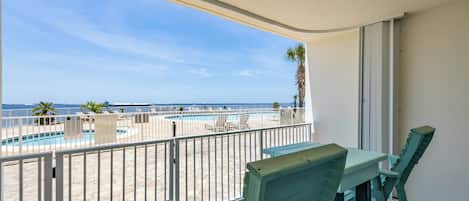 Een balkon met uitzicht op een zwembad en de oceaan.