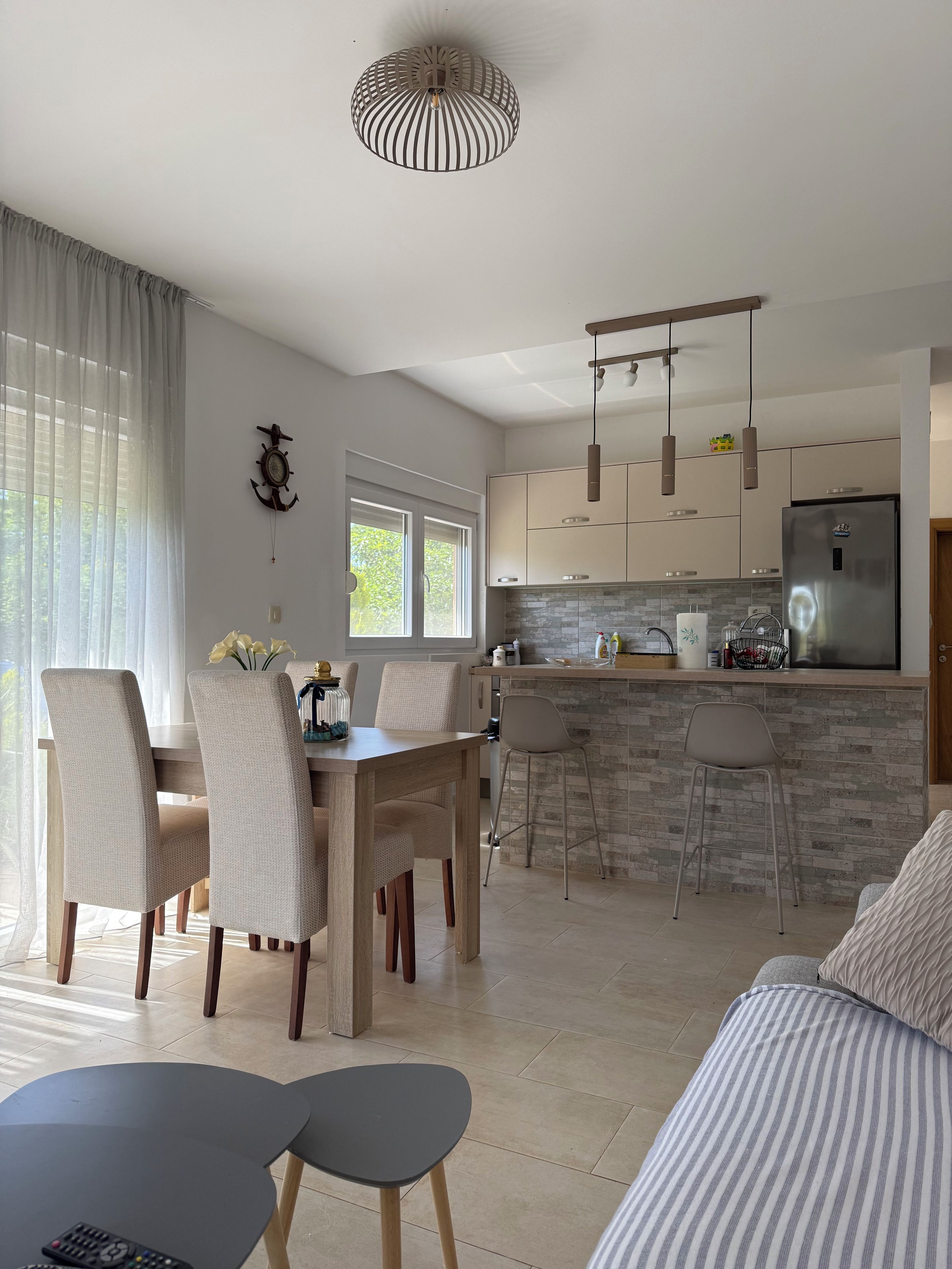 Une cuisine moderne dotée d’un îlot central, d’un coin repas avec des chaises et d’une grande fenêtre.