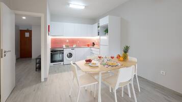 A modern kitchen with white cabinets, a red backsplash, and a dining area with a table set for two.