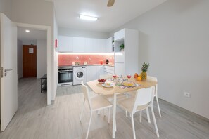 A modern kitchen with white cabinets, a red backsplash, and a dining area with a table set for two. - Holiday Home 'Casa Morango - Senhora Da Rocha' with Sea View, Wi-Fi and Air Conditioning (Porches)