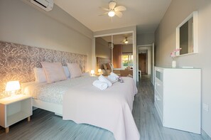 A hotel room with a bed, bedside tables, a mirror, and a desk with a vase of flowers. - Holiday Home 'Casa Morango - Senhora Da Rocha' with Sea View, Wi-Fi and Air Conditioning (Porches)