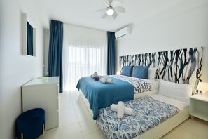 A bedroom with a bed, a desk, a chair, a ceiling fan, and a window with curtains. - Holiday Home 'Casa Azul 1 - Senhora Da Rocha' with Sea View, Wi-Fi and Air Conditioning (Porches)