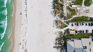 Vue aérienne d’une plage avec un parking et des bâtiments.
