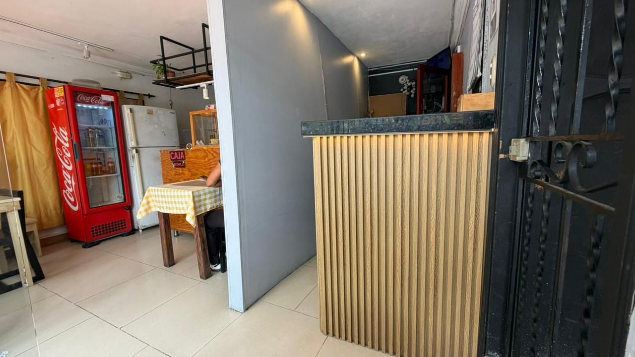 A room with a refrigerator, a table with a checkered tablecloth, and a wooden partition.