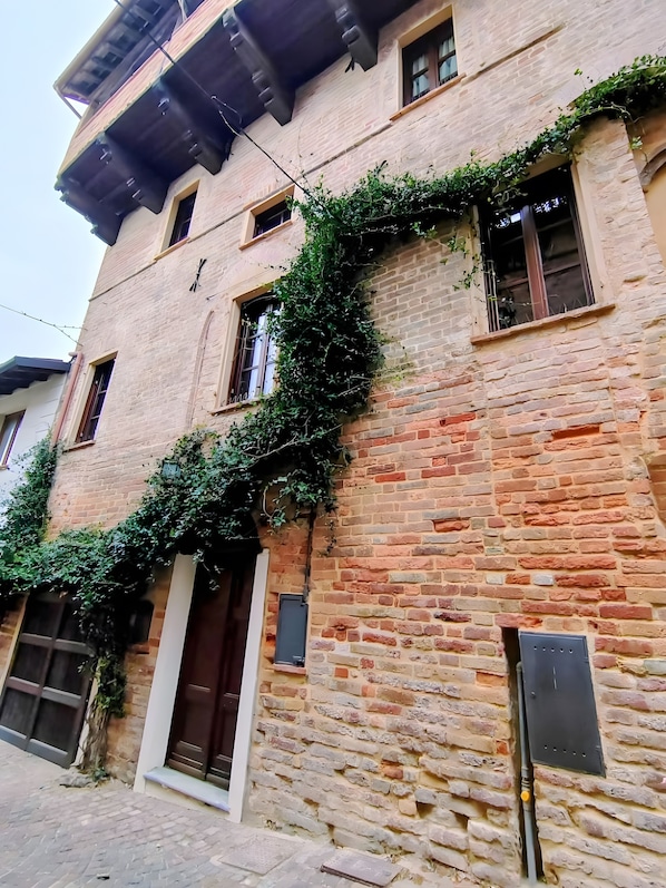 A multi-story building with a brick facade, a wooden door, and windows with shutters. - Holiday Home 'Casa Impera' with Mountain View, Wi-Fi and Air Conditioning (Montemagno)