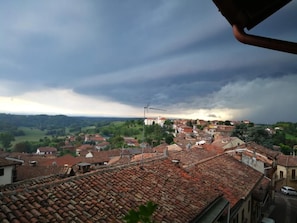 A view of a town with terracotta rooftops and a cloudy sky.