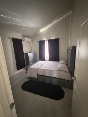 A bedroom with a bed, a dresser, a television, and a window with curtains. - The Black Pearl (Discovery Bay)