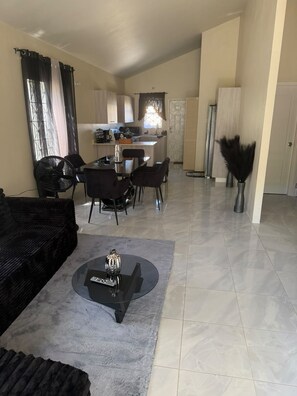 A living room with a black sofa, a coffee table, and a dining area with chairs and a table. - The Black Pearl (Discovery Bay)