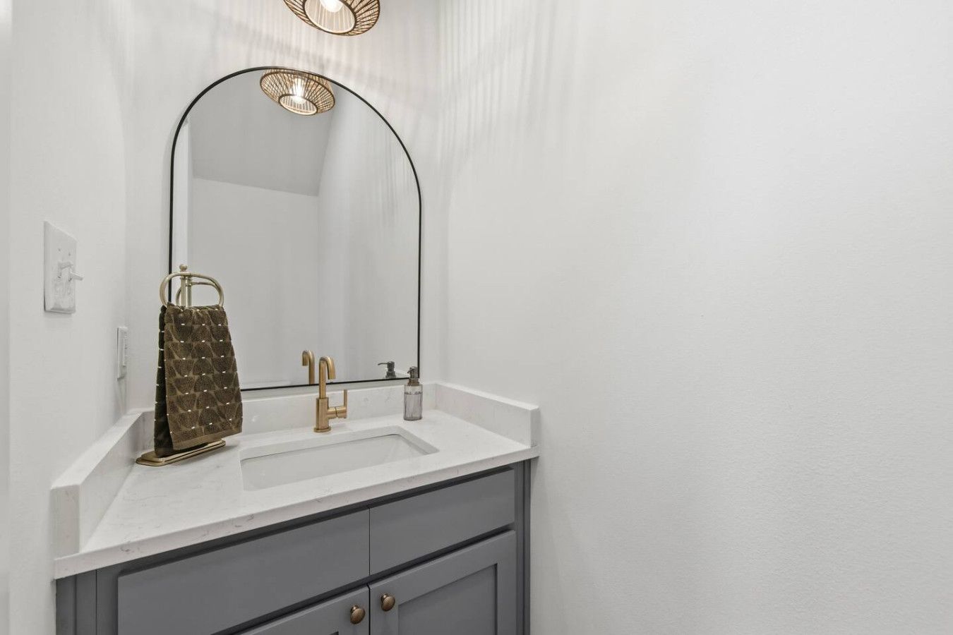A bathroom with a white vanity, a gold faucet, and a large mirror.