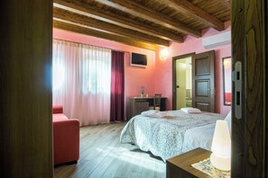 Ein Schlafzimmer mit einem Bett, einem Schreibtisch, einem Sessel und einem roten Sofa.