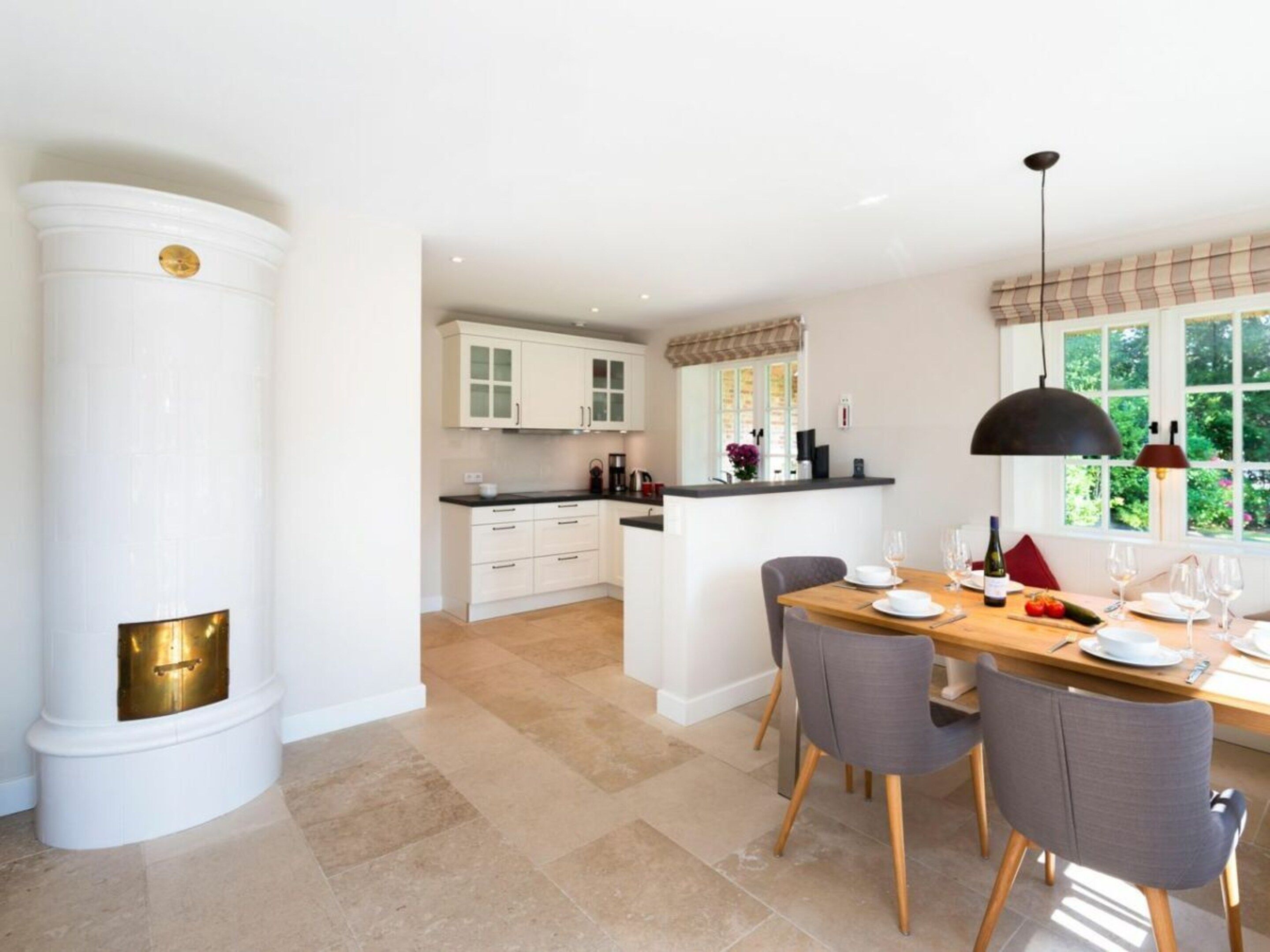 A modern kitchen with white cabinetry, a central island, and a dining area with a wooden table and chairs.