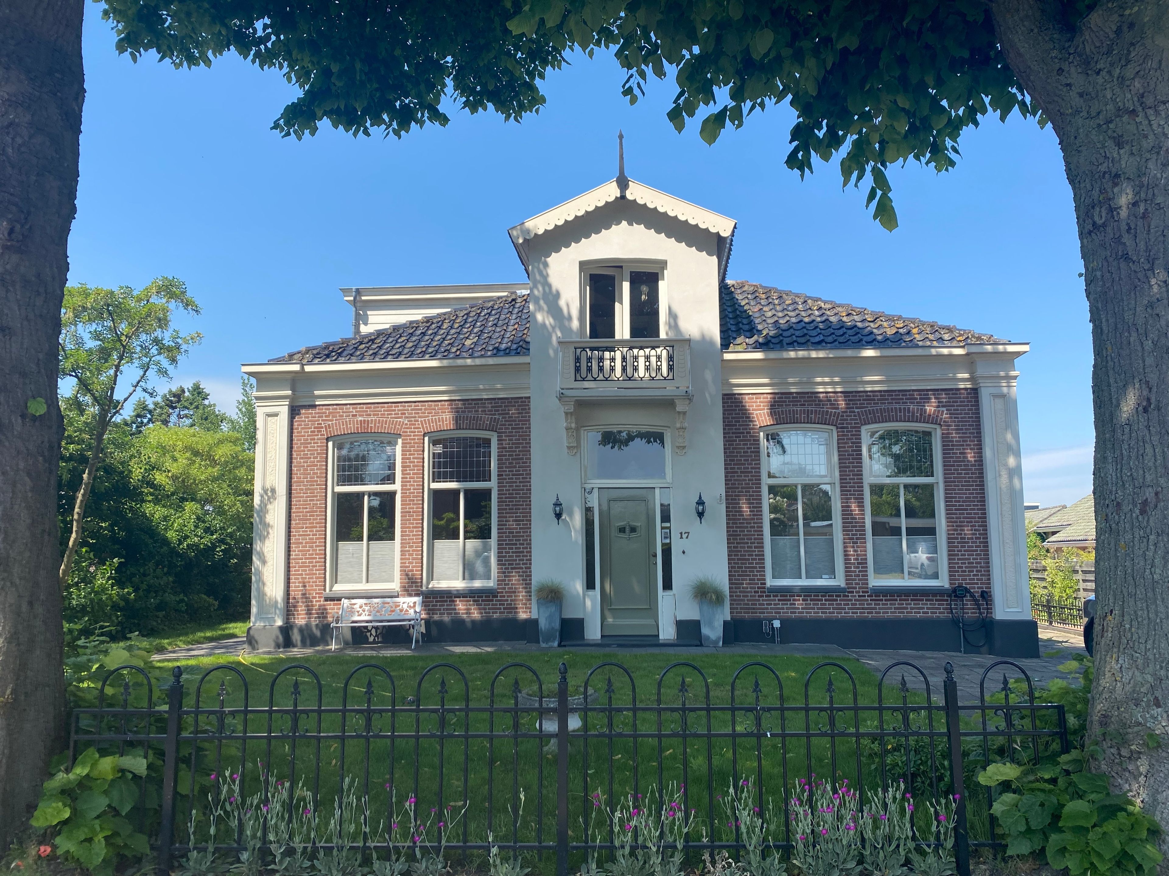 A two-story house with a brick facade, a white front door, and a small balcony.