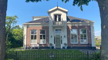 A two-story house with a brick facade, a white front door, and a small balcony.