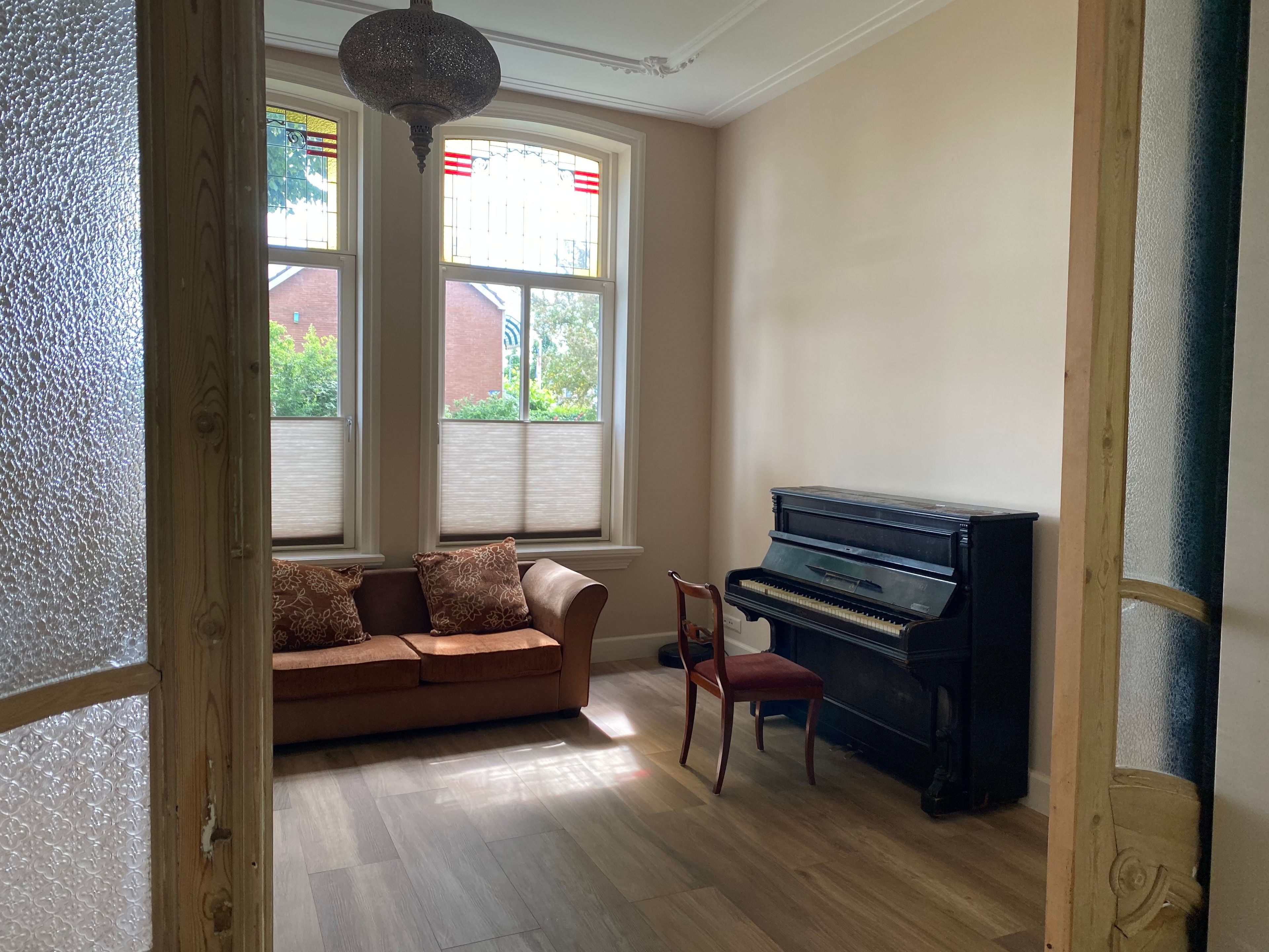 A room with a piano, a sofa, and a chair.