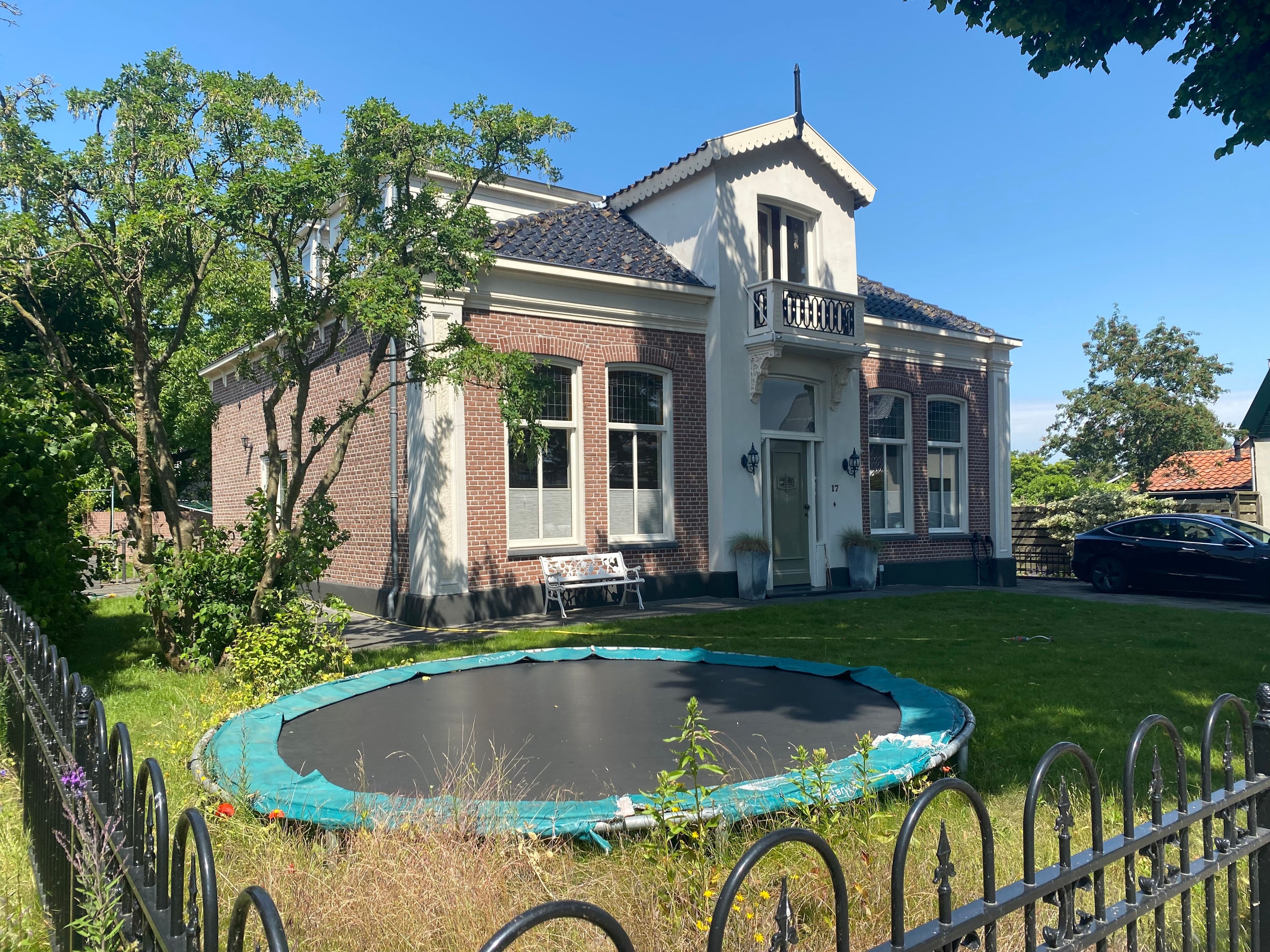 A house with a brick exterior, a front porch, and a trampoline in the yard.