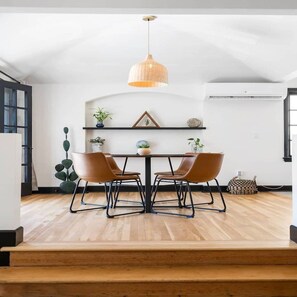 A dining area with a table, chairs, a hanging light fixture, and a staircase leading to an upper level. - Spanish Retreat Two Houses Together (San Diego)