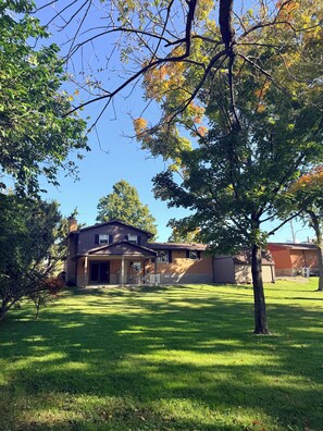 Een woonhuis met een tweelaags gebouw, een overdekte patio en een verzorgd gazon.