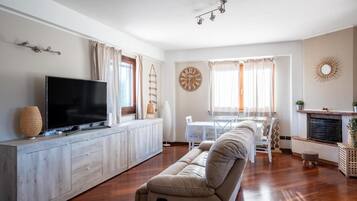 Ein modernes Wohnzimmer mit Flachbildfernseher, einer Couch, einem Esstisch und einem Kamin.