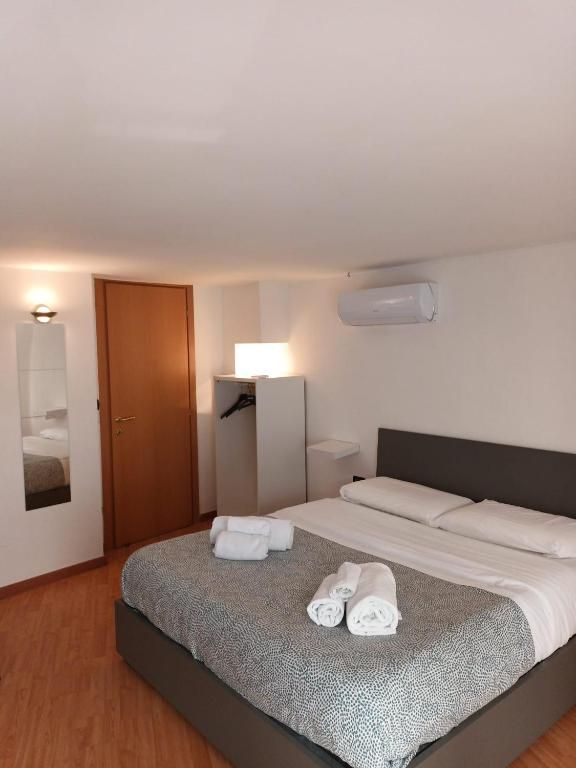 Una habitación de hotel con cama, armario, espejo y mesita de noche.